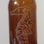 An etching of a sea horse on a beer bottle.