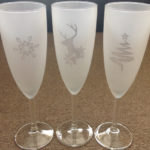 A Christmas tree, reindeer and snowflake reverse (negative) etched on Champagne glasses.